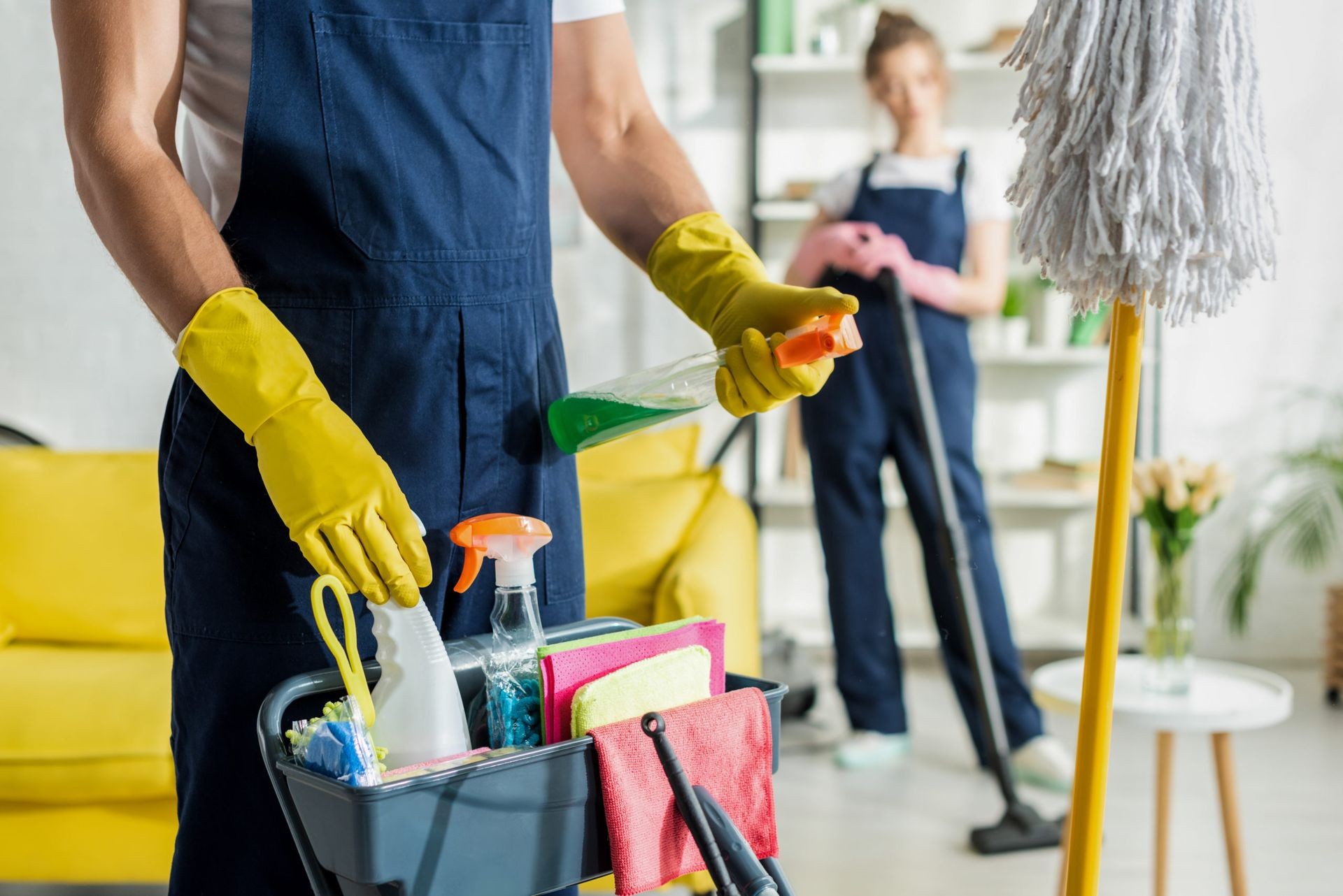 Cleaning staff in uniforms with supplies and equipment, wearing gloves, in a modern interior setting.